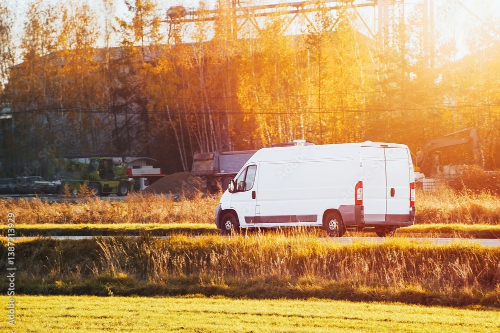 White van driving along autumn landscape