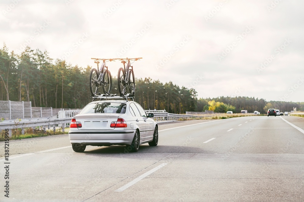 Sedan with bikes on roof traveling outdoors