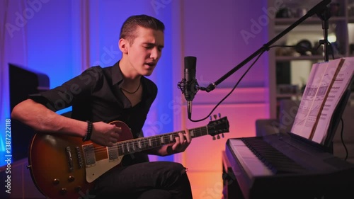Cinematic footage of teenager plays rock on a guitar. Teen boy plays a musical instrument.  Young man sings and plays the electric guitar at home. Musician records his composition in a music studio.