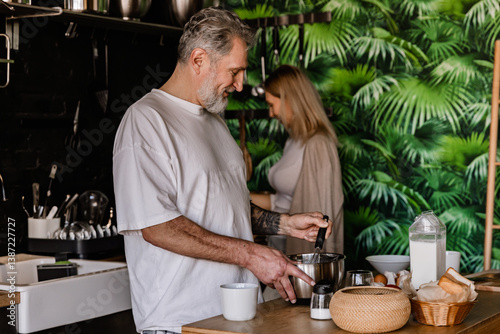 Obraz na plátne A middle-aged White man in his late 50s whipping up something in a metal bowl wi