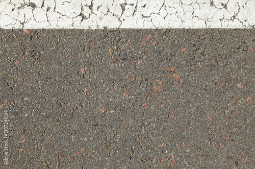 Asphalt surface, backdrop. An old asphalt with a white stripe applied with road paint. Road background with white stripe on top. Detailed texture of bitumen close-up. Road foundation on the street