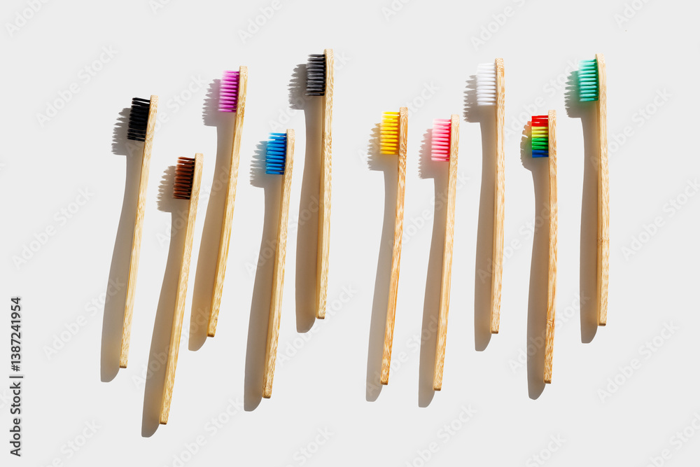 Eco friendly Bamboo toothbrushes with colored bristles at sunlight with dark shadows on white background. Sustainable living concepts, minimal style aesthetic photo, top view set wood oral brushes