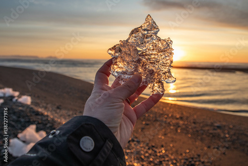 holding a piece of ice during sunrise at diamon beach in Iceland