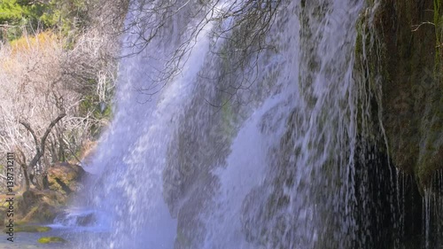 A river source cascades over rocks, creating  waterfall that sparkles in the sunlight