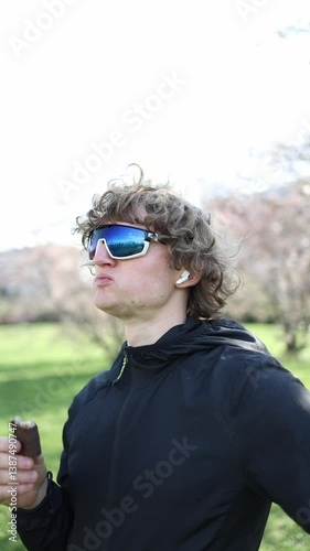 Craving kicks in as a young athlete in sporty sunglasses bites into a chocolate-covered snack outside on a sunny day showing the real face of sugar addiction in active lifestyles