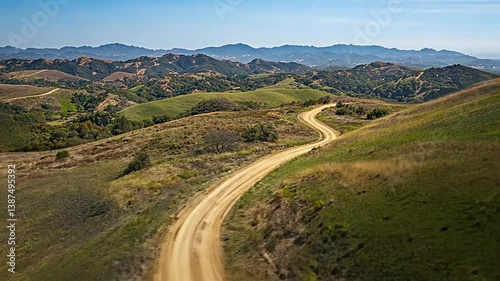 Scenic view of a dirt road winding through rolling hills and distant mountains