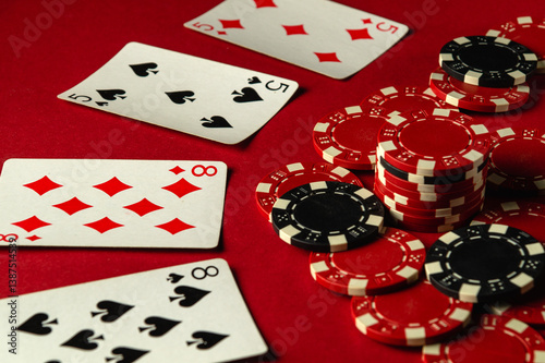 Foto A group of two pairs playing cards and poker chips are arranged on a red table, creating an atmosphere of excitement during a friendly gaming evening