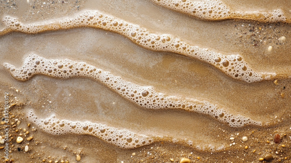 Obraz premium Close-Up View of Gentle Waves Rolling Over Golden Sand with Seafoam and Pebbles on a Tranquil Beach