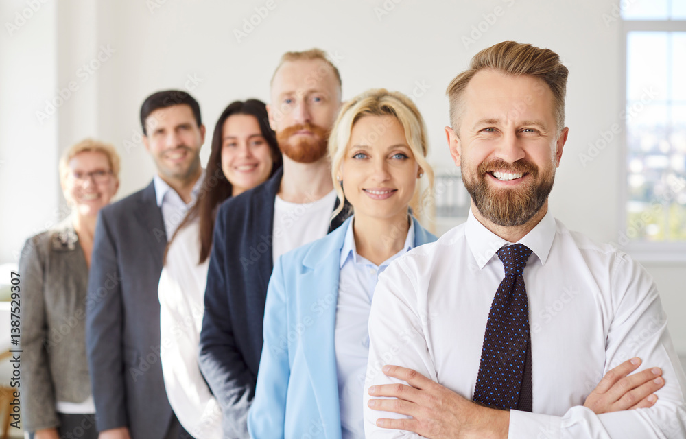 Portrait of confident smiling bearded business leader in shirt standing with arms crossed with joyful team standing in line behind him. Group of company employees representing unity and teamwork. Portrait of confident smiling bearded business leader in shirt standing with arms crossed with joyful team standing in line behind him. Group of company employees representing unity and teamwork.