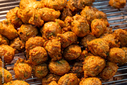Fotografie Crispy golden vegetable fritters frying in hot oil at a bustling street food mar