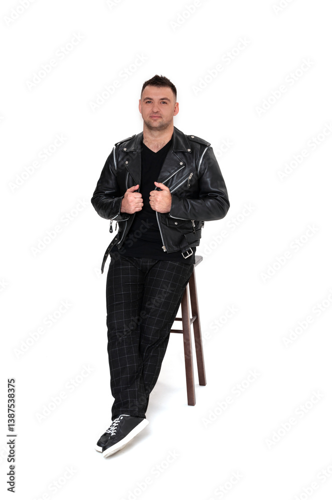 A handsome dark-haired man in a black leather jacket, black T-shirt, trousers and sneakers on a white background A handsome dark-haired man in a black leather jacket, black T-shirt, trousers and sneakers on a white background