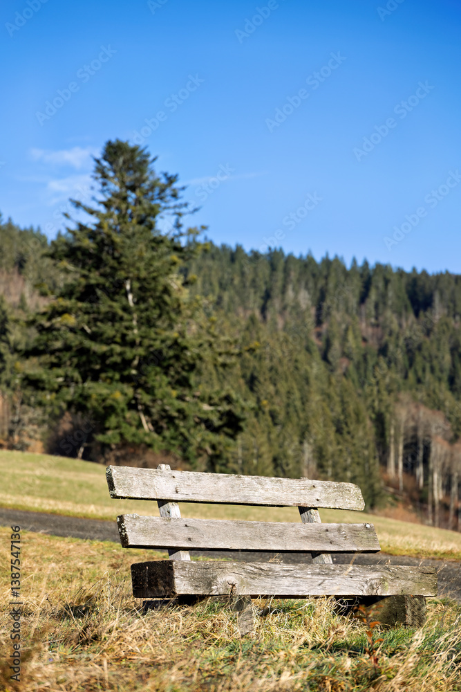 old, partially weathered wooden bench on a mountain meadow in the Black Forest with blurred background old, partially weathered wooden bench on a mountain meadow in the Black Forest with blurred background