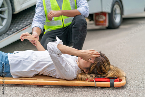 agent help injured woman using stretcher from car accident in asia countryside. asian woman in pain lifting by stretcher. unconscious woman lying got rescue from emergency officer from vehicle crash