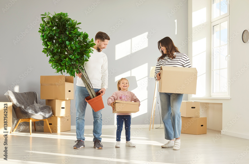 Happy family with child girl on moving day smiling with unpacked boxes and plant in hands in their new apartment. Home owners enjoying buying flat. Relocating, real estate, mortgage concept.