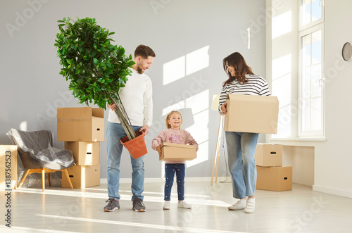 Obraz na płótnie Happy family with child girl on moving day smiling with unpacked boxes and plant in hands in their new apartment. Home owners enjoying buying flat. Relocating, real estate, mortgage concept. w salonie