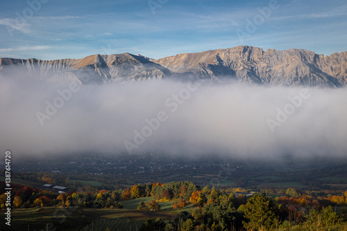 Mountains partially obscured by low clouds with autumn valley