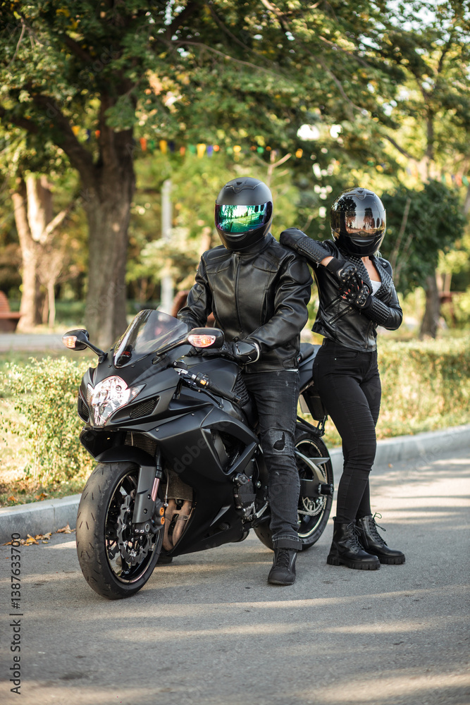 man and girl in helmets standing near motorcycle on open road man and girl in helmets standing near motorcycle on open road