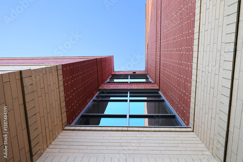 Abstract look or view straight upwards along side of building with u-shape design and clear blue sky