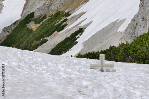 Sunny spring mountain landscape with snow sunken christian summit cross after a long cold winter with lots of snow. Styria, Austria