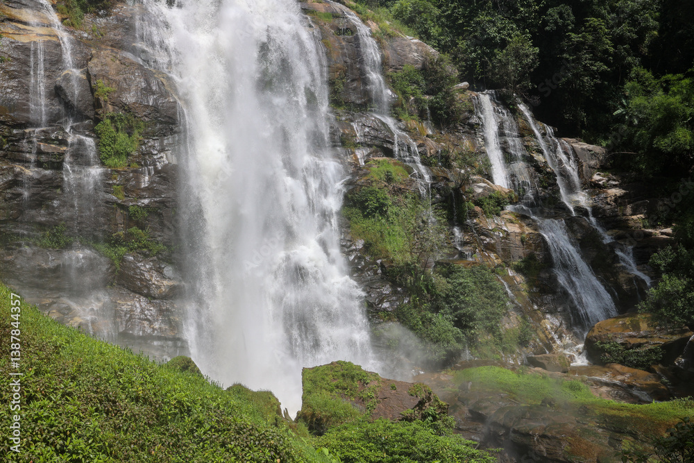 Obraz premium Waterfall Cascading Over Rugged and Rocky Terrain Surrounded by Natures Beauty.