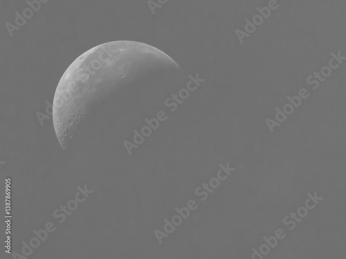 Obraz na płótnie Half moon in detail with visible craters against a soft gray sky. w salonie
