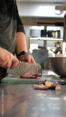 Chef cutting onion on cutting board in restaurant kitchen