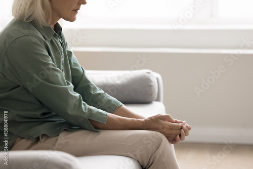 Aging problems. Close up cropped shot weak vulnerable elderly woman sit on sofa bent down at home in hospital deal with depression stress emotional strain health concern sorrow loneliness. Copy space