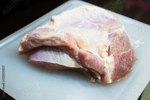 A large raw pork on a cutting board.