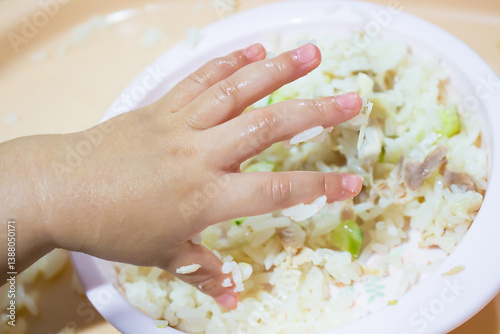 Asian baby using hand eating food. hand in food.	