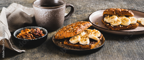 Obraz na płótnie Sweet sandwich with chocolate butter, banana and nuts on a plate on the table web banner w salonie