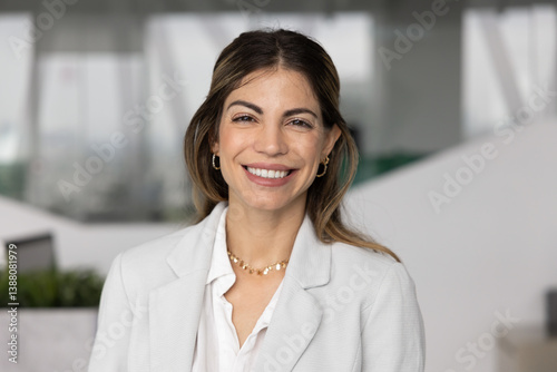 Happy beautiful Hispanic business leader woman posing for head shot with toothy smile, looking at camera, enjoying online conference chat. Confident businesswoman video call screen head shot