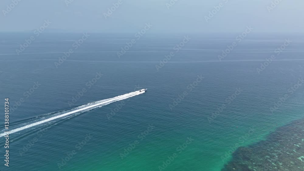 Aerial view of motor speedboat sailing in transparent turquoise sea waters near shoreline with reef in Thailand Aerial view of motor speedboat sailing in transparent turquoise sea waters near shoreline with reef in Thailand