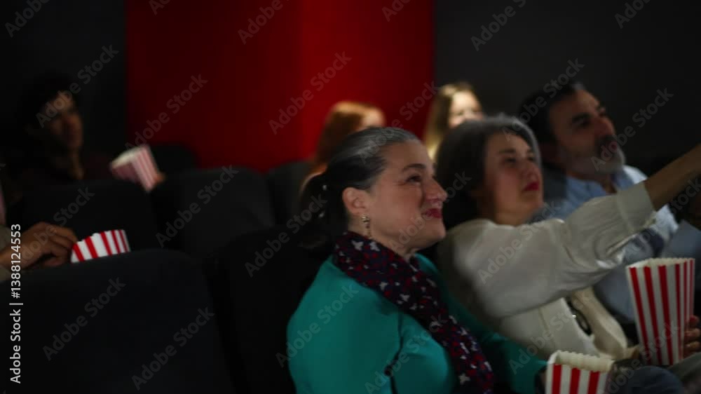 Audience enjoying movie and eating popcorn in theater Audience enjoying movie and eating popcorn in theater