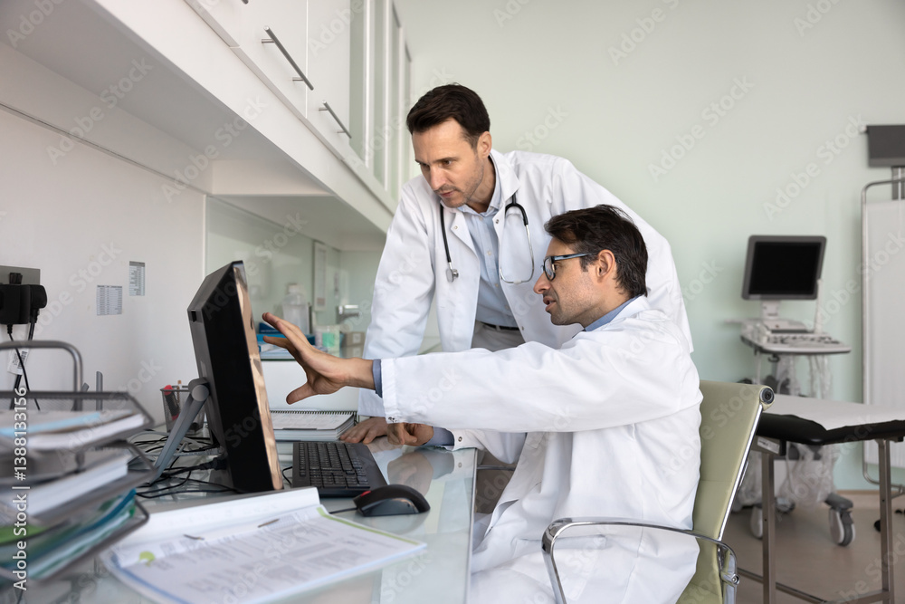 Two doctors engaged in teamwork using computer, discussing patient diagnosis, reviewing medical records, symptoms, and test results, exchanging opinions and knowledge during meeting in consulting room