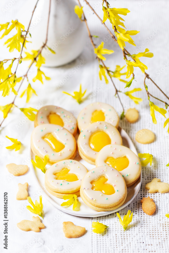 Easter egg cookies with lemon orange curd, covered with white icing and forsythia flowers.