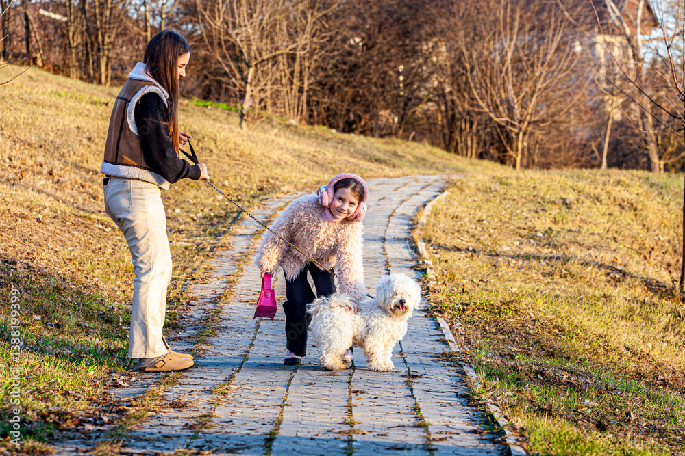 Fototapeta premium One spring day with a very beautiful sun, two girls were surprised while they were walking with a very beautiful white dog. The girls were the happiest to have such an animal friend.
