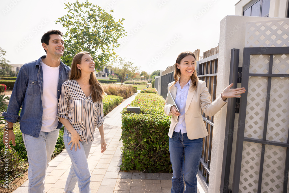 Realtor female inviting young Hispanic married couple to enter high-tech house, look around and make decision to buy or rent contemporary property. Modern real-estate showcasing to potential buyers Realtor female inviting young Hispanic married couple to enter high-tech house, look around and make decision to buy or rent contemporary property. Modern real-estate showcasing to potential buyers