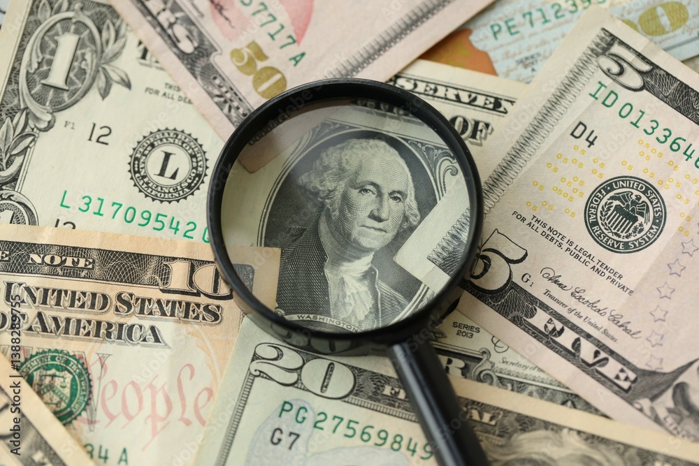 Big amount of United States USD dollar bills and magnifying glass Big amount of United States USD dollar bills and magnifying glass