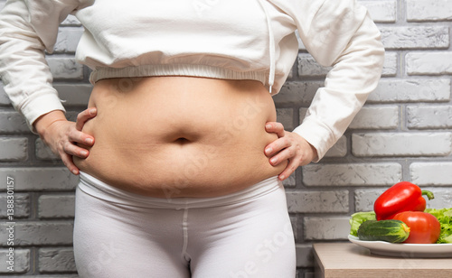 Close-up of the belly with fat. Women's health. A woman dressed in sports clothes shows off her imperfect body after giving birth