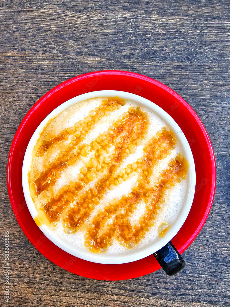 Cappuccino in red cup on wooden table