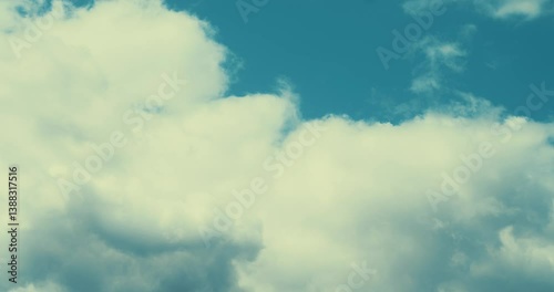 Blue Sky with Clouds Timelapse. Fluffy white clouds move gracefully across a bright blue sky in a peaceful natural scene. Calm, time, weather, and open air.
