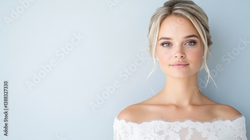A blonde woman with an elegant updo wears a white lace off-the-shoulder top. The simple composition emphasizes her beauty. High-resolution image with soft, natural lighting. The style is clean and