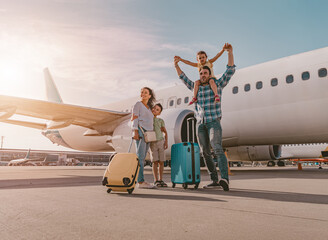 A happy family is at the busy airport, surrounded by luggage, eagerly preparing for their next adventure