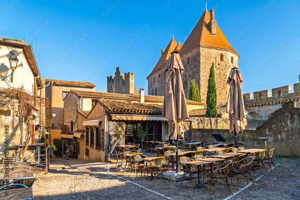 Fototapeta premium Shops and sidewalk cafes in the picturesque medieval La Cite' village inside the walls of the Carcassonne Castle at Carcassonne, France.