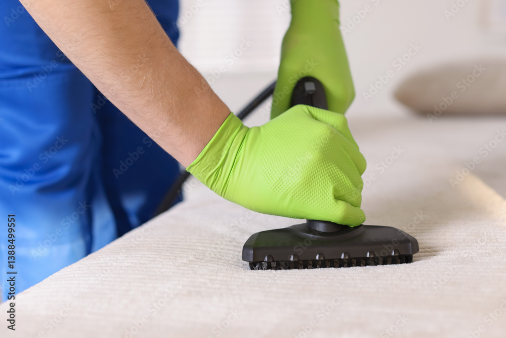 Professional janitor cleaning sofa with vapor steam system at home, closeup