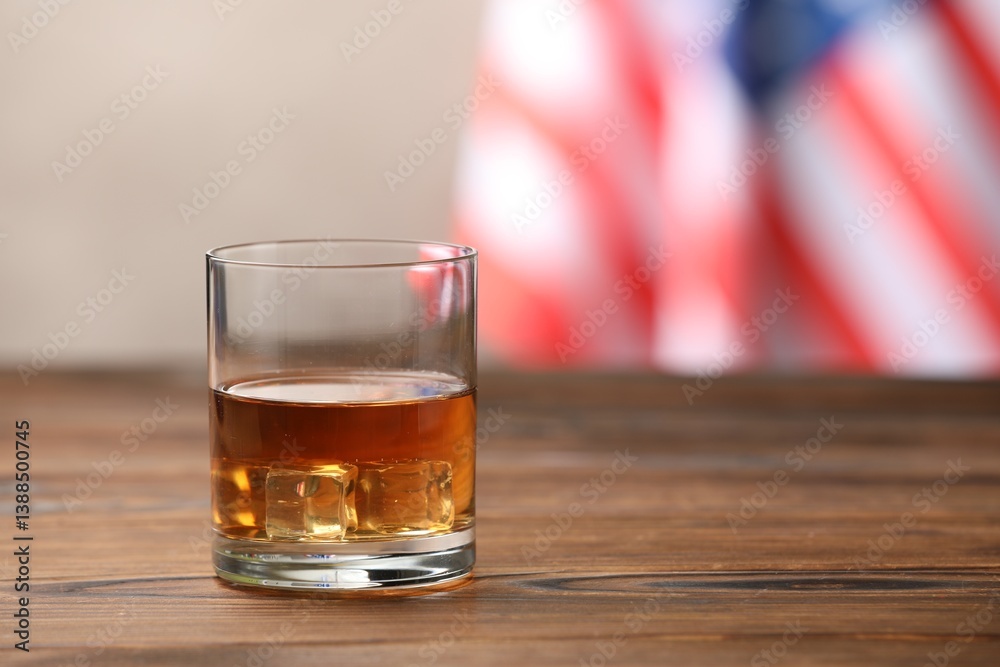 Glass of whiskey on wooden table against American flag. Space for text Glass of whiskey on wooden table against American flag. Space for text