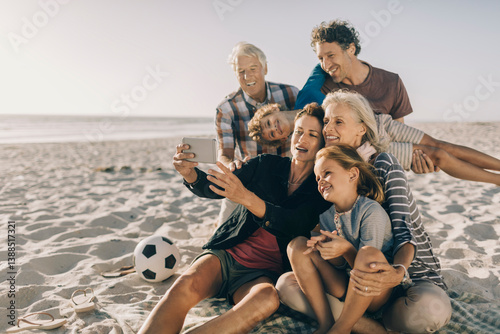 Multigenerational family taking a selfie with a smartphone on a sandy beach on their holiday vacation