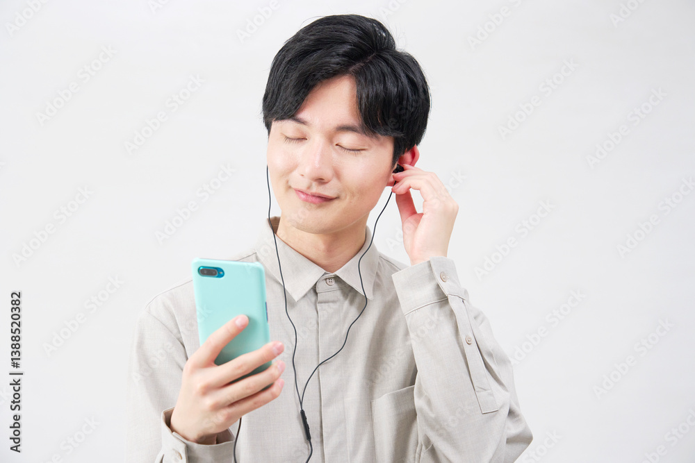 イヤホンをつけて音楽を聴く20代男性 白背景 イヤホンをつけて音楽を聴く20代男性 白背景
