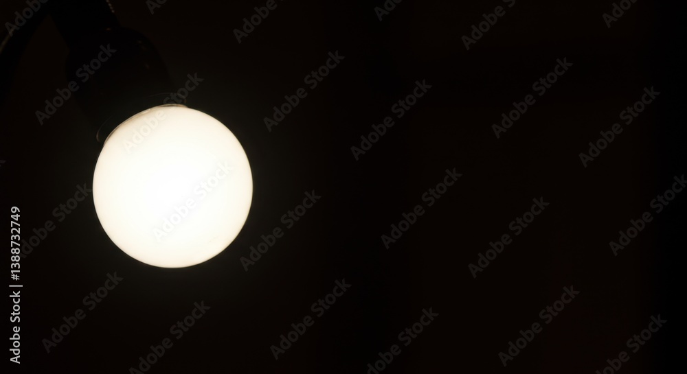 Illuminated Orb in the Dark: A Glowing Lightbulb Against Pitch Black Background
