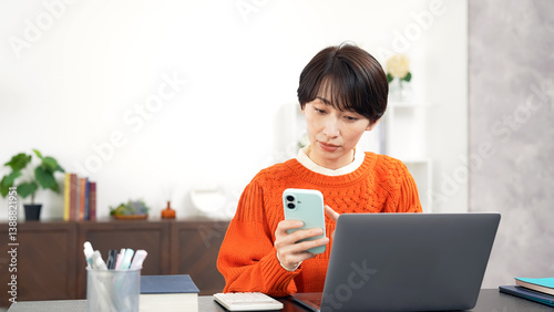スマホとノートパソコンを使うミドル女性